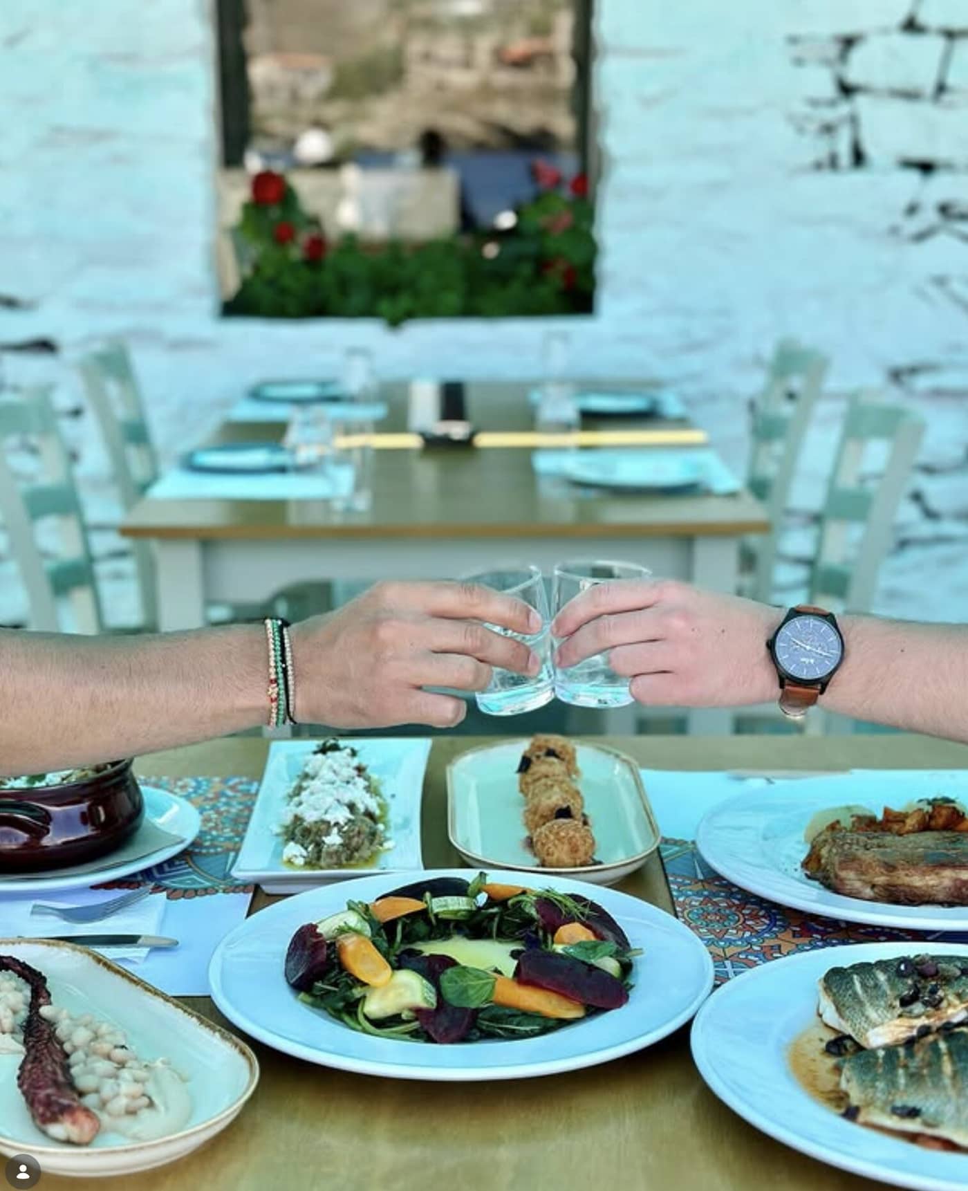 Πρόποση με τσίπουρο πάνω από τραπέζι γεμάτο μεζέδες και θαλασσινά